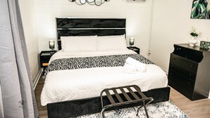 Une chambre bien rangée, avec un lit, des tables de chevet, une commode et une chaise.