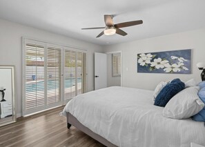 A bedroom with a bed, a ceiling fan, a painting, and a view through the window blinds. - Stylish 4BR Pool Oasis,ASU,Spring Training! Old Town Scottsdale 10 minutes away. (Tempe)