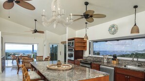 Una cocina espaciosa con una isla grande, armarios de madera y vista al océano.