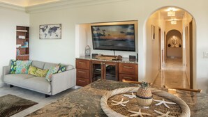 Una sala de estar con un sofá, un televisor y una cesta decorativa sobre una mesa de mármol.