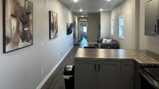 A modern kitchen with dark wood cabinets, a stainless steel countertop, and a built-in oven. - Downtown Lofts (International Falls)