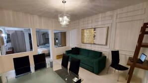 A modern living room with a glass dining table, green sofa, and a chandelier. - Casa Blanca Grand (Acapulco de Juárez)