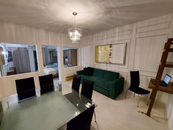 A modern living room with a glass dining table, green sofa, and a chandelier. - Casa Blanca Grand (Acapulco de Juárez)