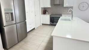 A modern kitchen with white cabinetry, stainless steel appliances, and a central island.