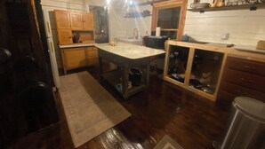 A kitchen with wooden cabinets, a marble countertop, and a wooden dining table.
