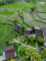 Un pueblo tradicional con campos de arroz en terrazas, casas con tejados de paja y una fuente central.