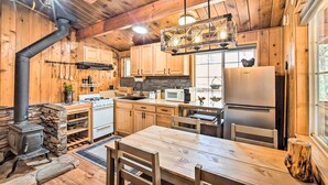 A rustic wooden cabin interior with a kitchen featuring a stove, microwave, and refrigerator. - Steps to trails • Fireplace • Pet & kid friendly (Big Bear)