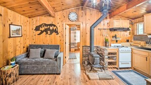 A cozy cabin interior with a wooden interior, a fireplace, a kitchen with a stove, and a couch. - Steps to trails • Fireplace • Pet & kid friendly (Big Bear)