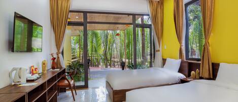 A hotel room with two beds, a desk, a refrigerator, and a large window with curtains.
