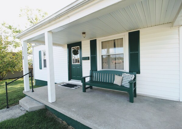 A porch with a green bench, a white door with green shutters, and a mailbox. - Cottage In Downtown Georgetown Within Walking Distance Of Shops and Restaurants (Georgetown)