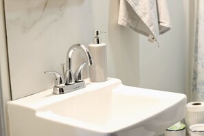 A bathroom with a white sink, chrome faucet, and a soap dispenser. - Cottage In Downtown Georgetown Within Walking Distance Of Shops and Restaurants (Georgetown)