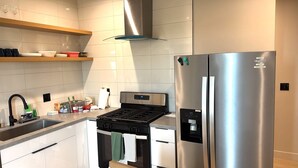 Una cocina moderna con un refrigerador de acero inoxidable, un horno empotrado y una estufa a gas.