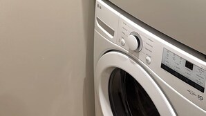 Una lavadora y secadora apiladas, con paneles de control y pantalla digital.
