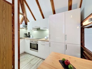 Eine moderne Küche mit weißen Schränken, einem eingebauten Ofen und einem Holzespeisetisch mit Obst.