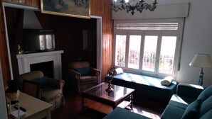 Uma sala de estar com lareira, sofá, mesa de centro e televisão.
