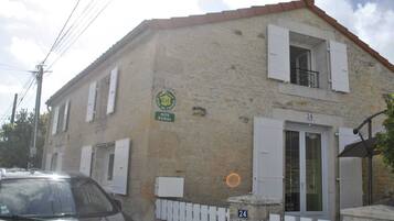 Un edificio de dos plantas con fachada de piedra, un cartel que indica que es una casa rural tipo 'Gîte' y el número 24 en la puerta.