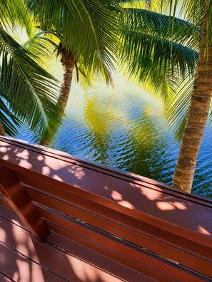 A wooden deck with a view of a calm body of water and palm trees. - Rainbow Holiday Resort (Nadi)