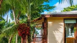 A two-story wooden house with a balcony, surrounded by tropical vegetation. - Rainbow Holiday Resort (Nadi)