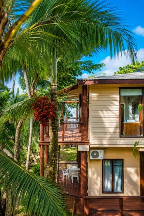 A two-story wooden house with a balcony, surrounded by tropical vegetation. - Rainbow Holiday Resort (Nadi)