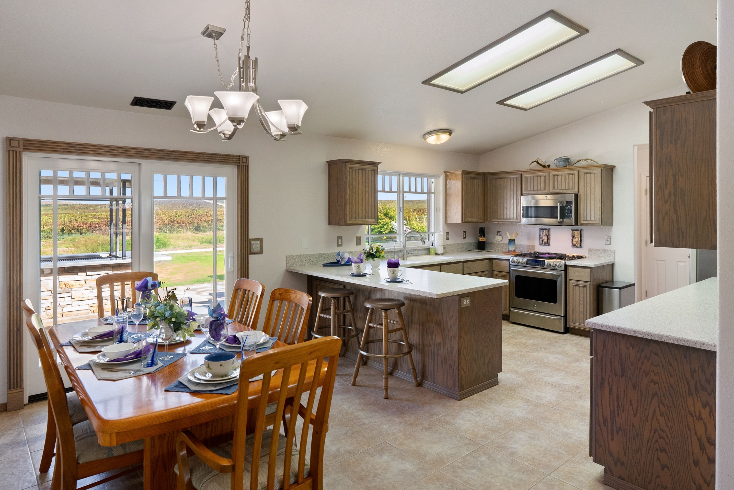 A spacious kitchen with wooden cabinets, a central island, and a dining area with a table set for four.