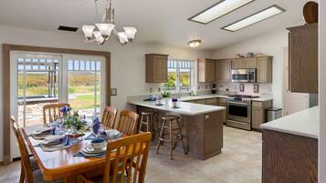 A spacious kitchen with wooden cabinets, a central island, and a dining area with a table set for four.