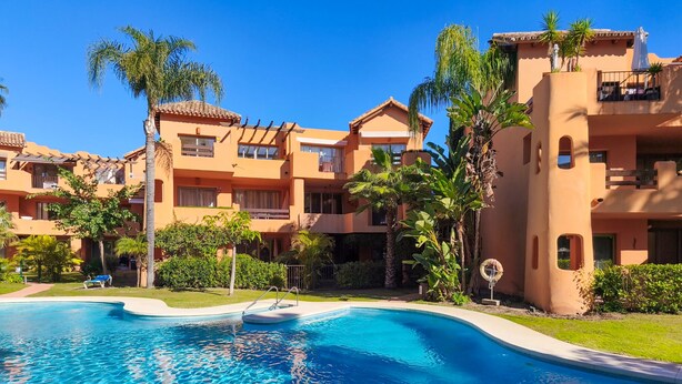 Ein Resort mit Swimmingpool, Palmen und orangen Gebäuden.