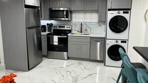 A modern kitchen with stainless steel appliances, grey cabinets, and a marble floor.