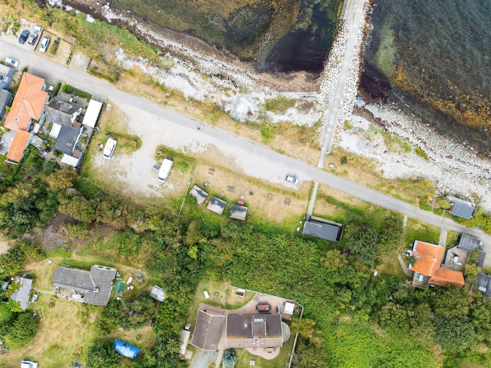 An aerial view of a residential area with houses, a road, and a beach.