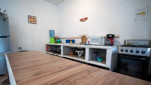 A kitchen with a wooden countertop, a stove, a microwave, and various kitchen items on shelves.