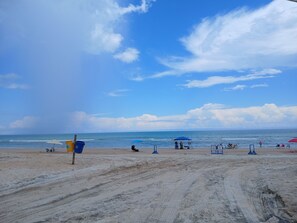 A beach with a clear sky, a sandy path, and beach chairs.