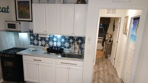 A compact kitchen with white cabinets, a microwave, and a stove.