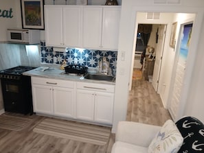 Cocina compacta con armarios blancos, microondas y estufa.