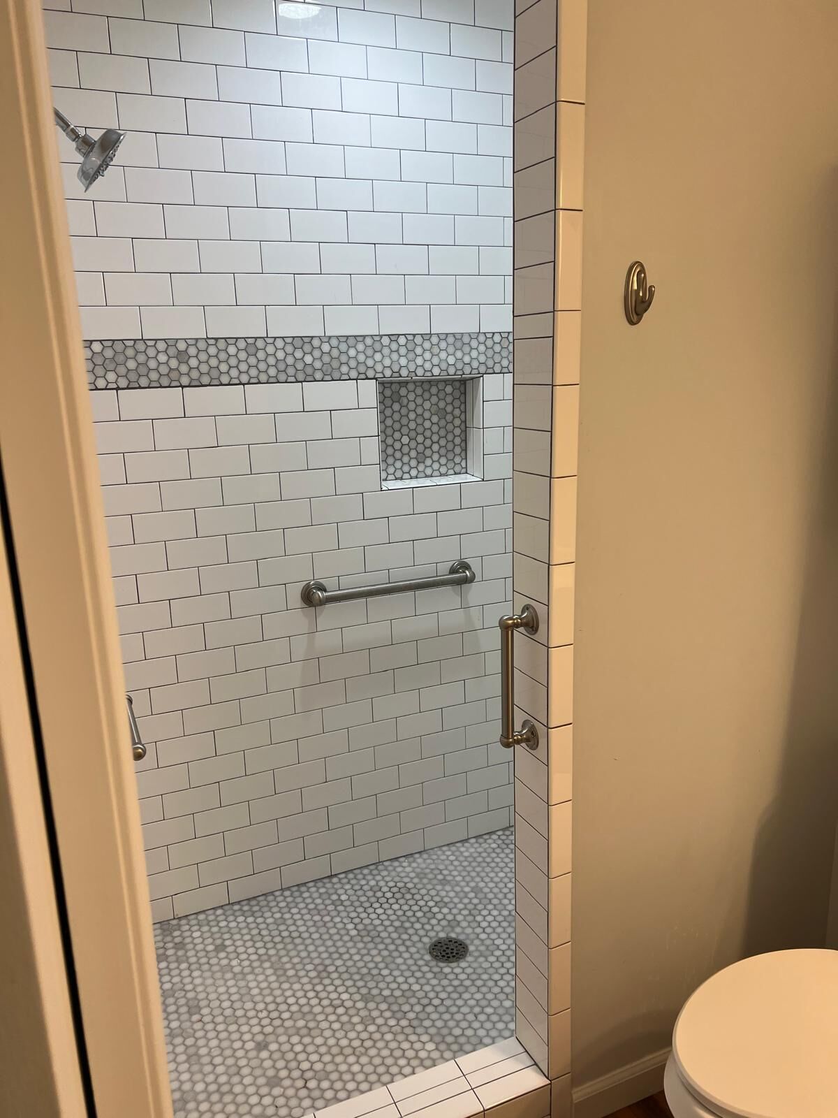 A small, enclosed shower area with white tiles and a hexagonal pattern on the floor.