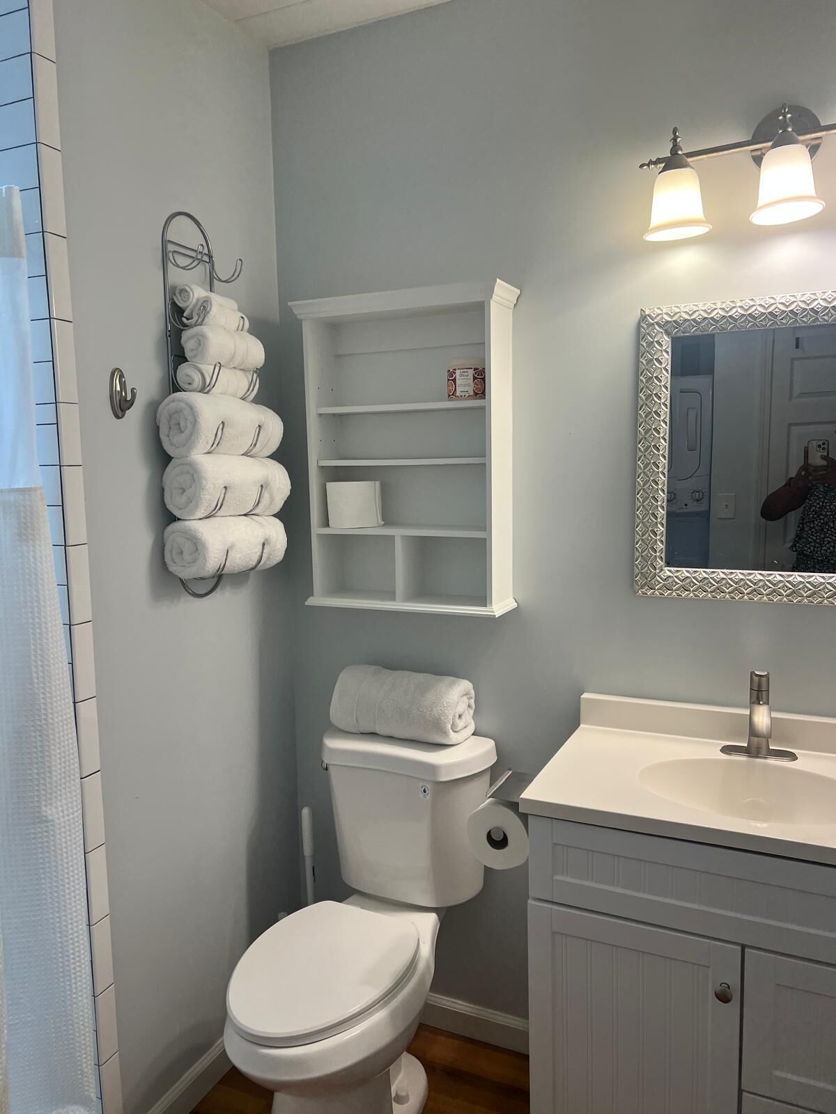 A bathroom with a toilet, a sink, a mirror, and a towel rack with multiple towels.