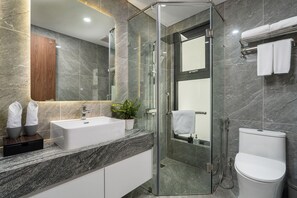 Une salle de bain moderne avec une douche à parois de verre, un lavabo blanc et des toilettes.