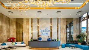A hotel reception area with a modern design, featuring a marble reception desk, blue seating, and a unique chandelier. - ARAVELLE SUITES (Hanoi)
