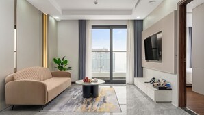 A modern living room with a sofa, a coffee table, and a TV mounted on the wall. - ARAVELLE SUITES (Hanoi)