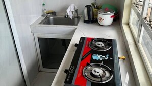 Cocina compacta con estufa a gas, un lavamanos y un ventanal pequeño.