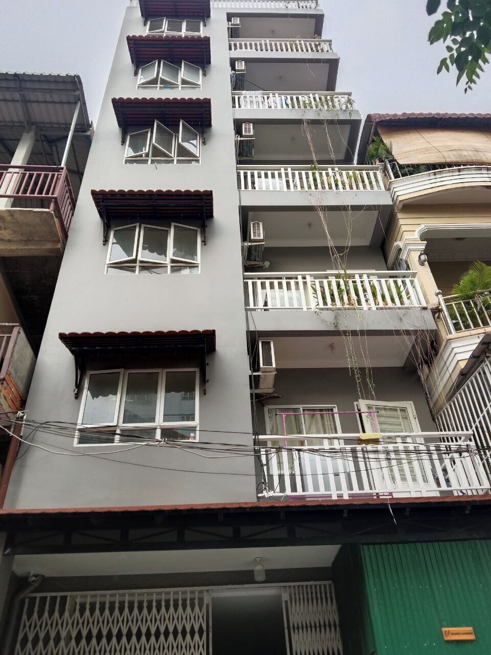 A multi-story building with balconies, air conditioning units, and a green door.