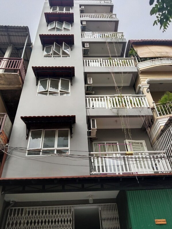 A multi-story building with balconies, air conditioning units, and a green door.
