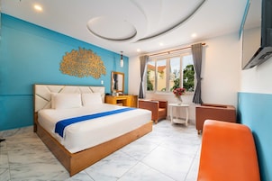Quarto de hotel moderno com uma cama grande, uma escrivaninha, uma cadeira e vista para o exterior.