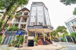 Um hotel com fachada moderna, várias varandas e uma entrada destacada com degraus.