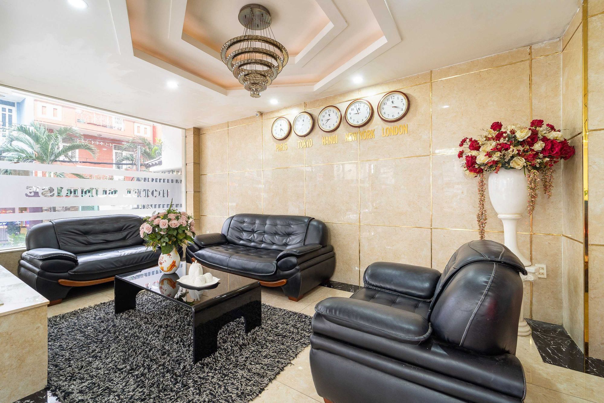 A lobby with leather sofas, a coffee table, a vase of flowers, and clocks displaying times from various cities.
