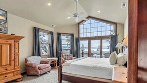 Une chambre avec un grand lit, une armoire en bois, une petite table, une chaise et une vue sur l’extérieur grâce à une grande fenêtre.