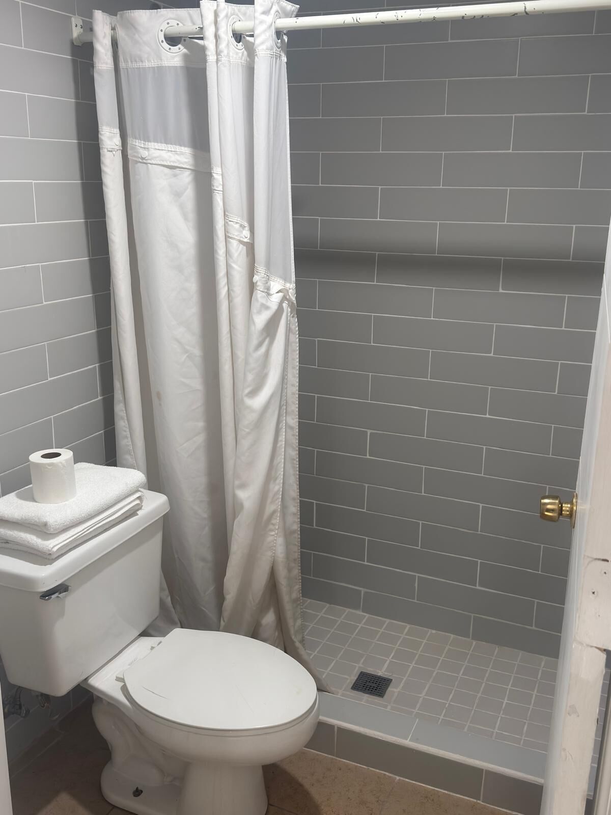Un baño con inodoro, cortina de ducha y pared de ducha con azulejos.