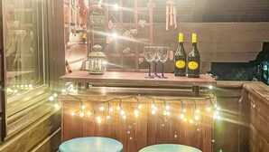 Un espace bar avec des tabourets, un comptoir et des bouteilles de vin.