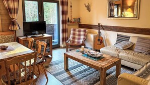 Un salon chaleureux avec un téléviseur, des meubles en bois, une guitare et une cheminée.