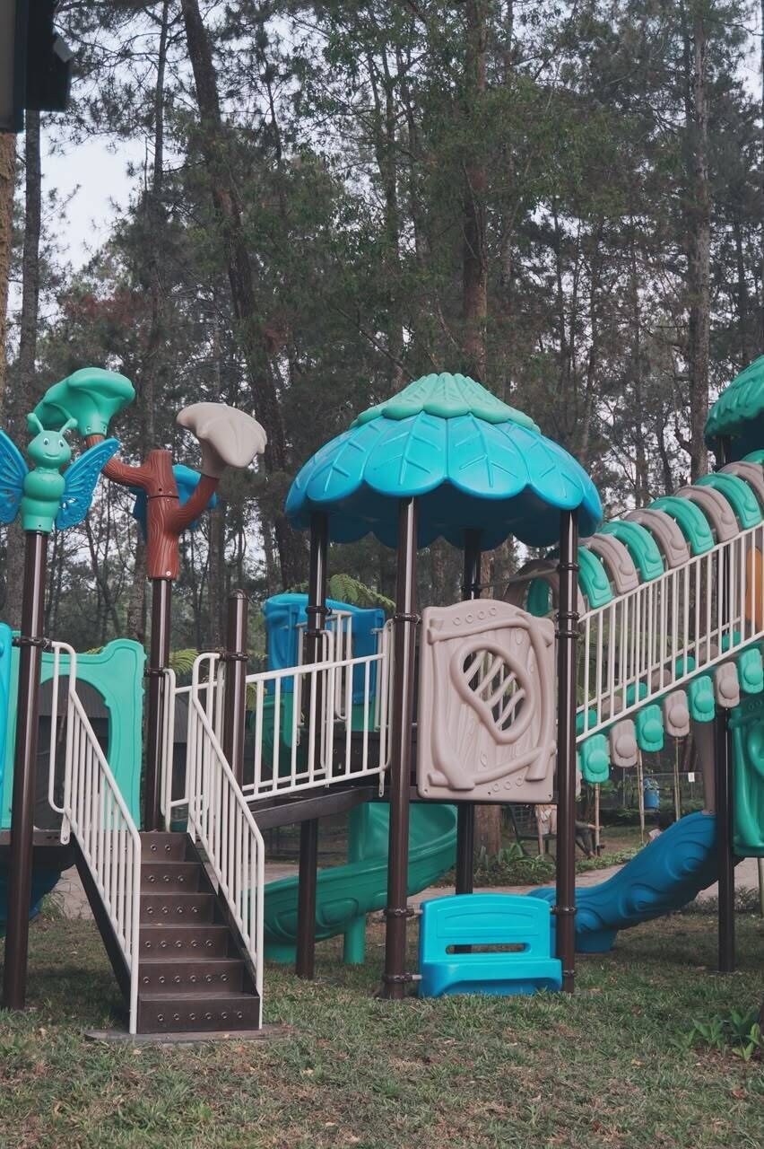 A children's play area with a slide, climbing steps, and a small shelter.