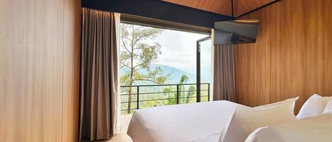 A modern hotel room with a large bed, wooden walls, and a balcony with a scenic view.