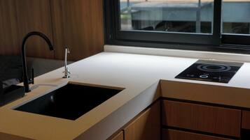A modern kitchen with a black sink, a window, and a built-in induction cooktop.